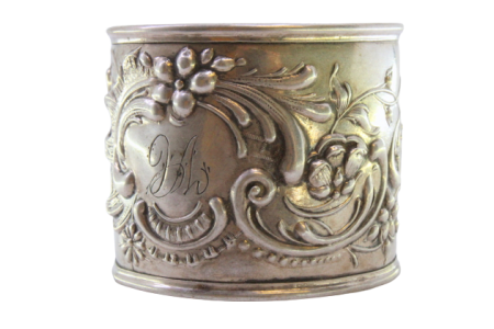 Argola de guardanapo em prata com motivos florais relevados envolvendo cartela para monograma.